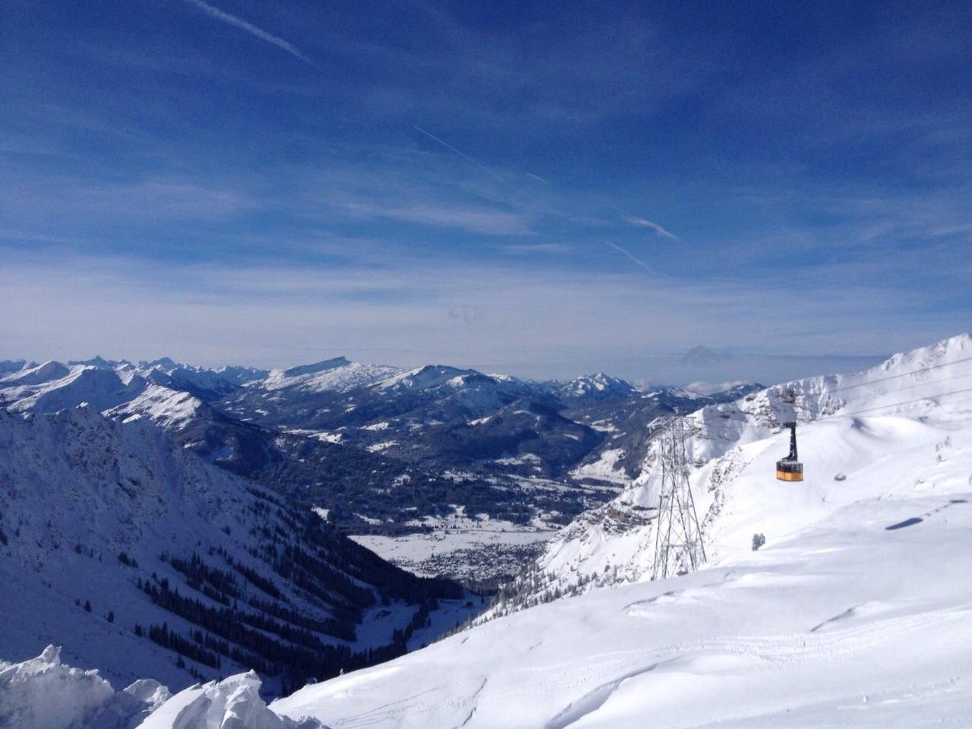 Gelbe Pendelbahn-Gondel über einem verschneiten Allgäuer Tal, schneebedeckte Bergketten im Hintergrund