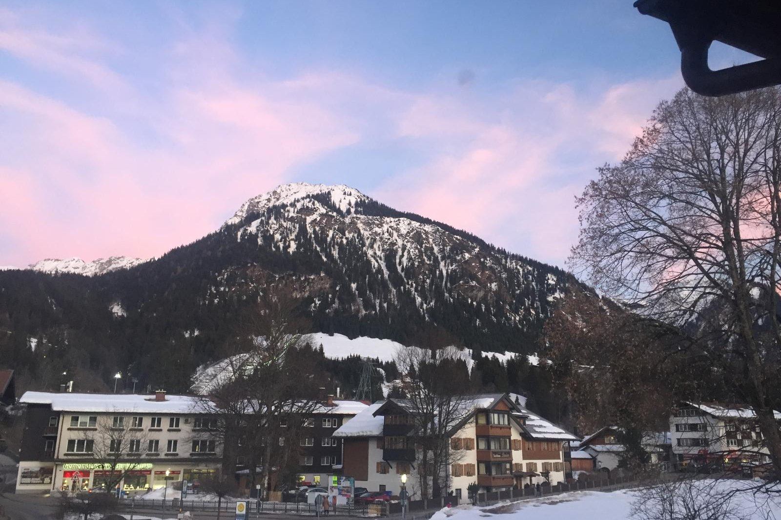 Schattenberg im winterlichen Sonnenuntergang mit rosa Wolken, der Ortskern von Oberstdorf im Vordergrund