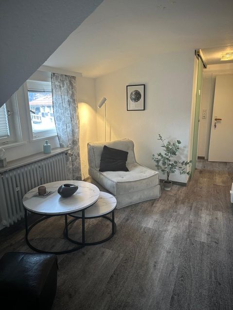 Wohnbereich mit Cord-Sessel, Marmor-Couchtisch und Eukalyptus-Pflanze, Fensternische links.