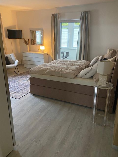 Hauptschlafzimmer mit 180er Boxspringbett, weißer Kommode und Sitzecke im Hintergrund.